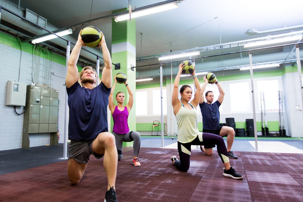 People in studio doing medicine ball exercise.